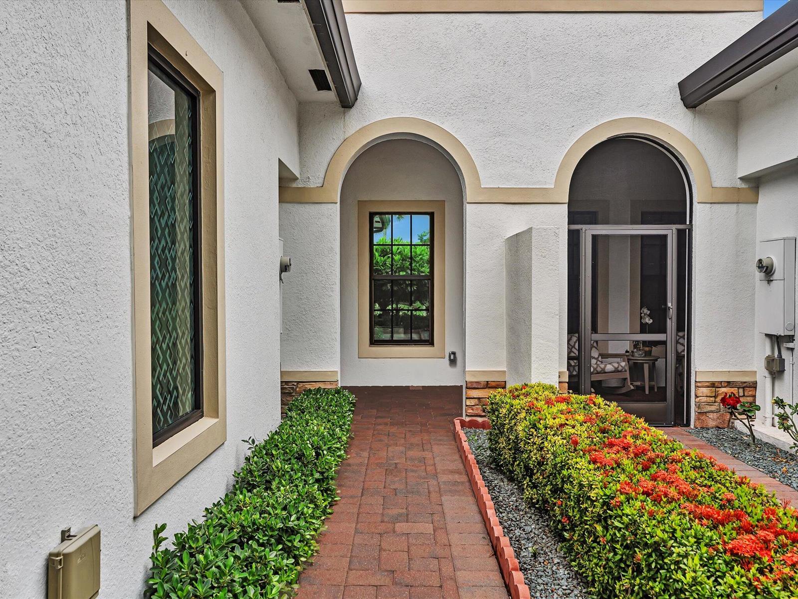 A brick walkway leads to an arched entryway and a screened door on a stucco home — 7457 S Blue Spring Drive, Parkland FL 33067, PARKLAND, FL
