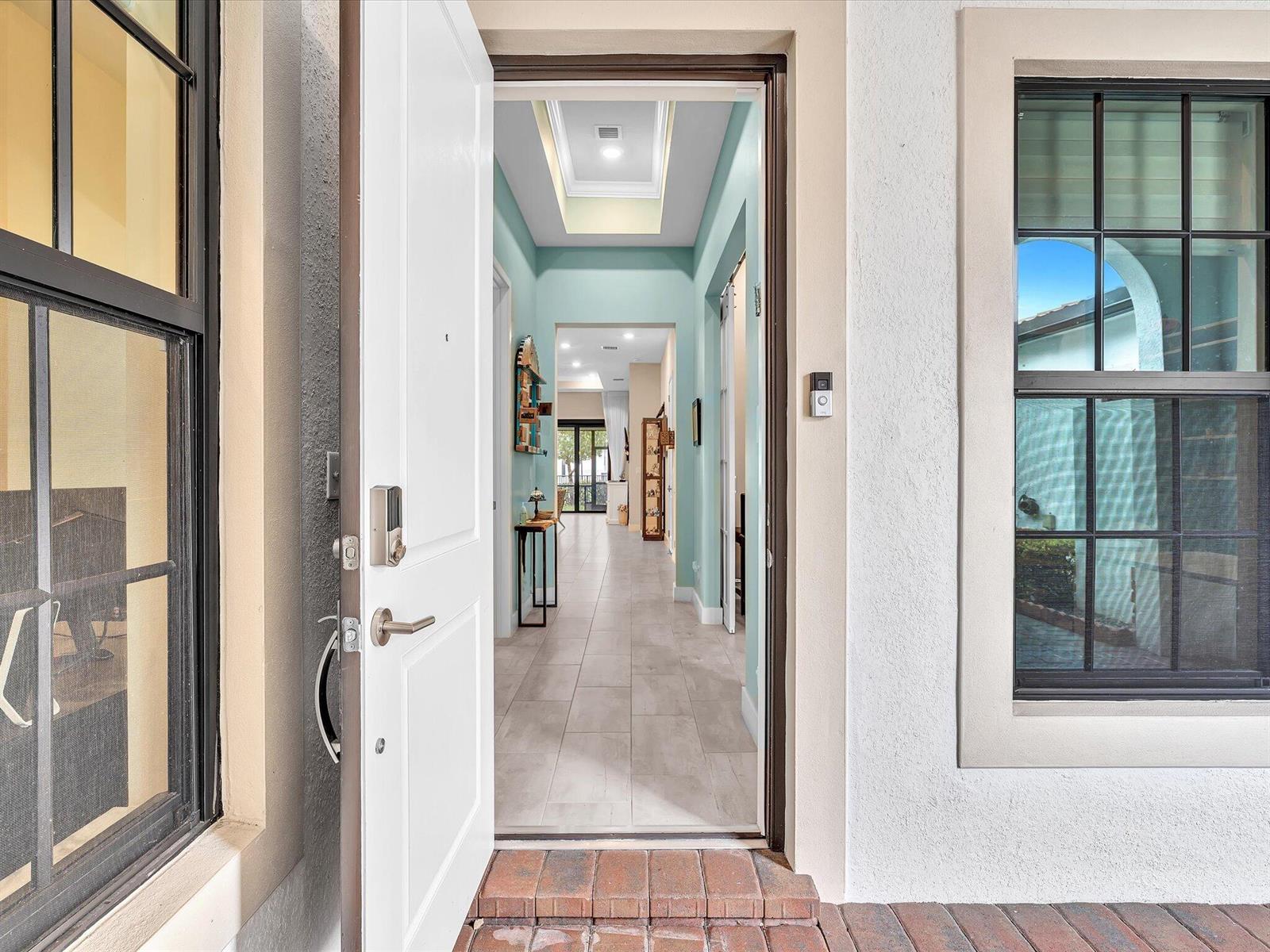 An open front door reveals a tiled entryway leading to a hallway with light blue walls — 7457 S Blue Spring Drive, Parkland FL 33067, PARKLAND, FL