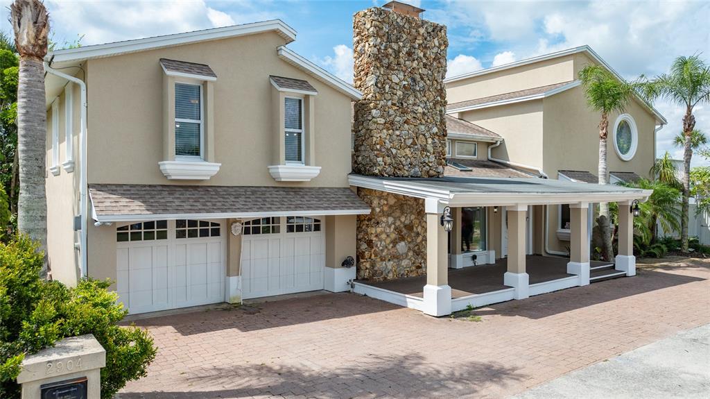 A two-story house features a stone chimney, a covered porch, and a two-car garage — 2904 S PENINSULA DR, DAYTONA BEACH SHORES, FL