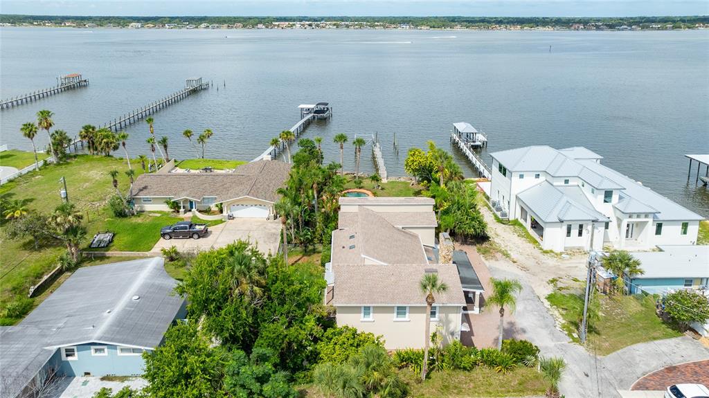 An aerial view shows waterfront houses with private docks along a large body of water — 2904 S PENINSULA DR, DAYTONA BEACH SHORES, FL