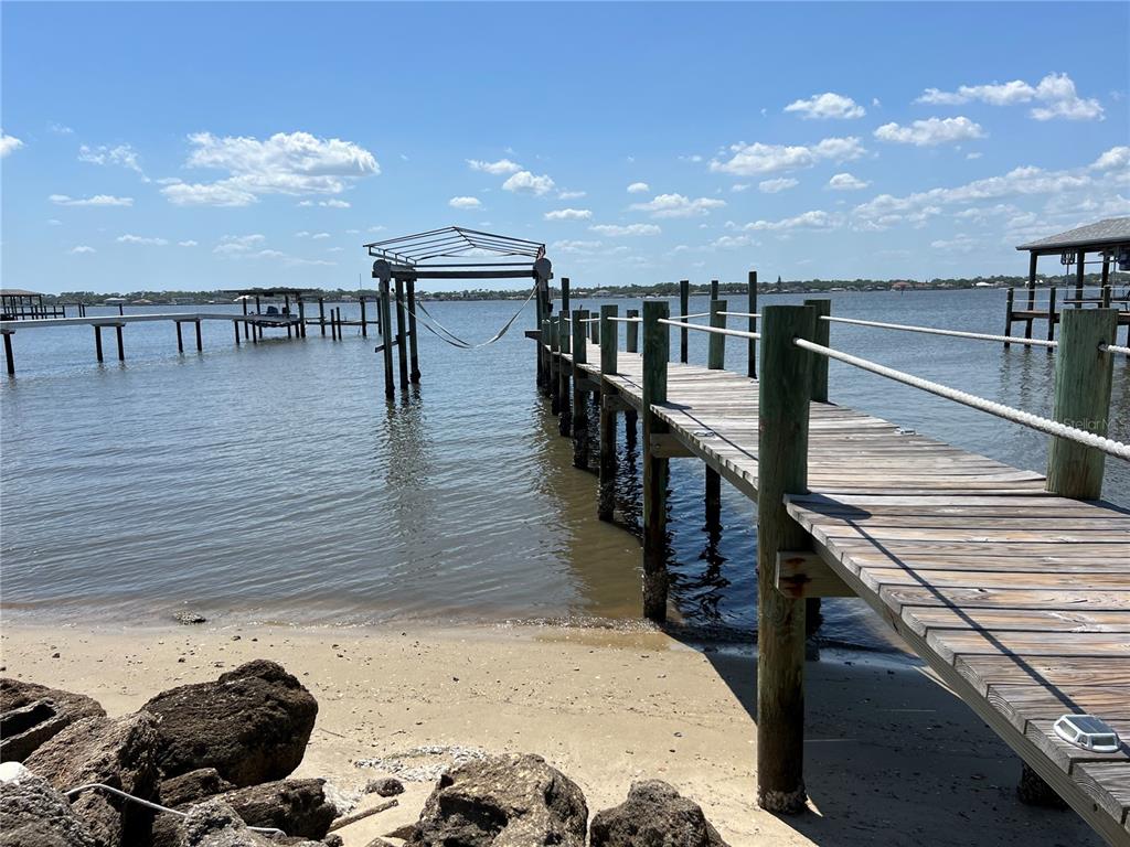 A wooden dock extends into a body of water with a hammock underneath a frame — 2904 S PENINSULA DR, DAYTONA BEACH SHORES, FL