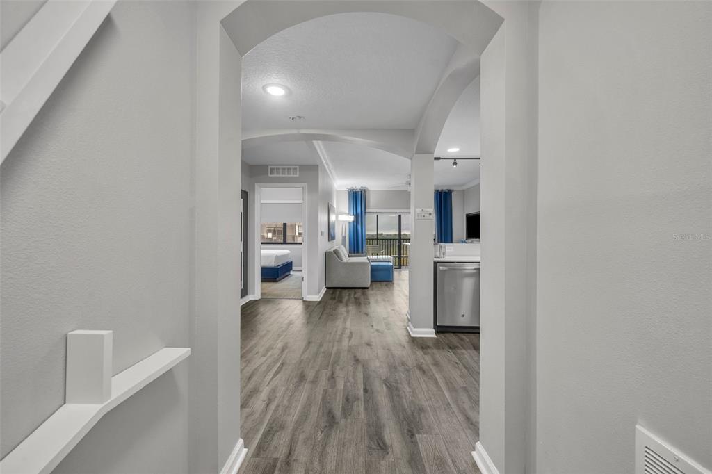 A view through an arched doorway into an open-concept living area with wood-look flooring — 14501 GROVE RESORT AVENUE UNIT 1703, WINTER GARDEN, FL