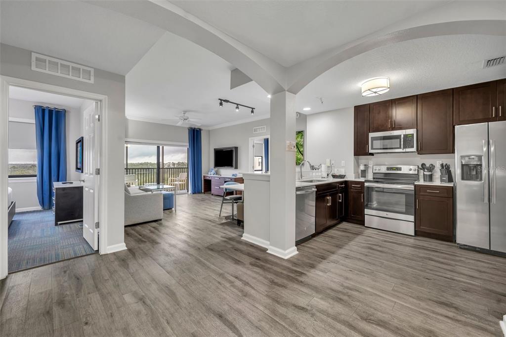 A kitchen with dark wood cabinets and stainless steel appliances opens to a living area — 14501 GROVE RESORT AVENUE UNIT 1703, WINTER GARDEN, FL
