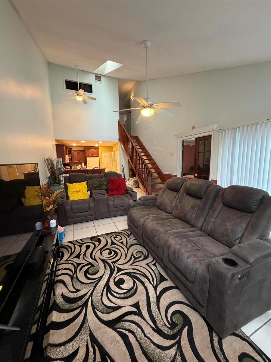 An open-concept living area features white tile floors, a red wainscot, and a wooden staircase — 2035 Winners Circle, North Lauderdale FL 33068, NORTH LAUDERDALE, FL