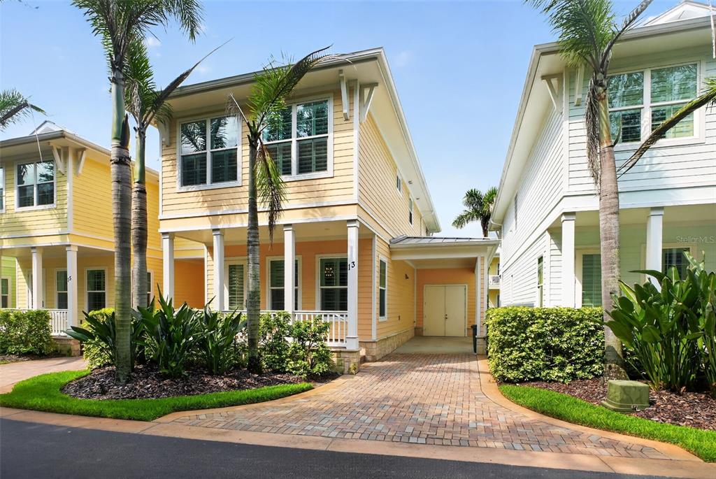 A yellow two-story house with a brick driveway, a front porch, and palm trees — 13 OLD FEGER DRIVE UNIT 13, NEW SMYRNA BEACH, FL