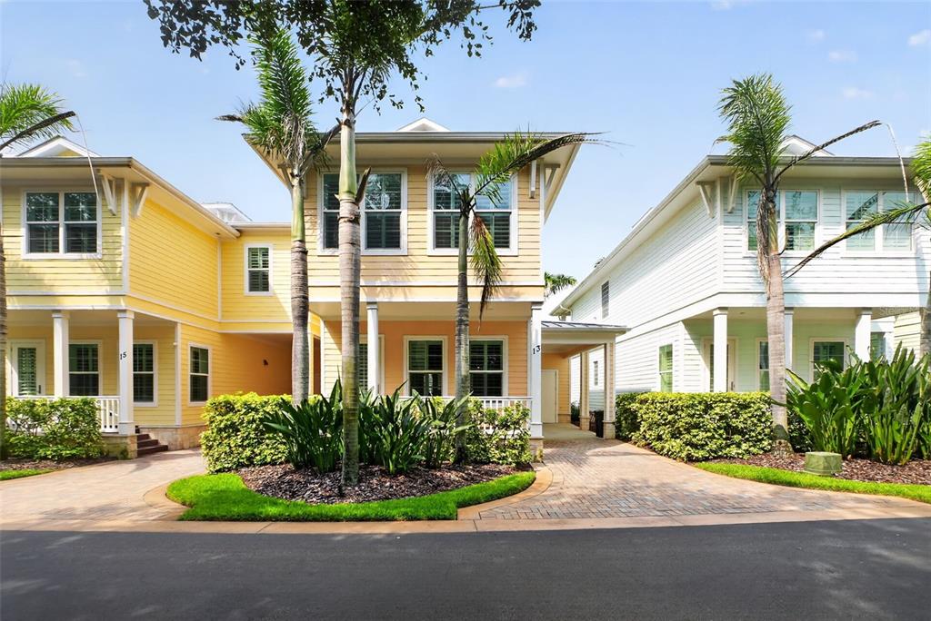 Three adjacent two-story houses with pastel siding, front porches, and palm trees in a driveway — 13 OLD FEGER DRIVE UNIT 13, NEW SMYRNA BEACH, FL