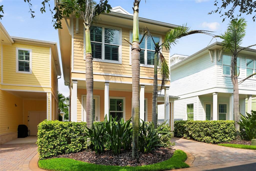A two-story yellow house with a covered porch, palm trees, and a manicured hedge — 13 OLD FEGER DRIVE UNIT 13, NEW SMYRNA BEACH, FL
