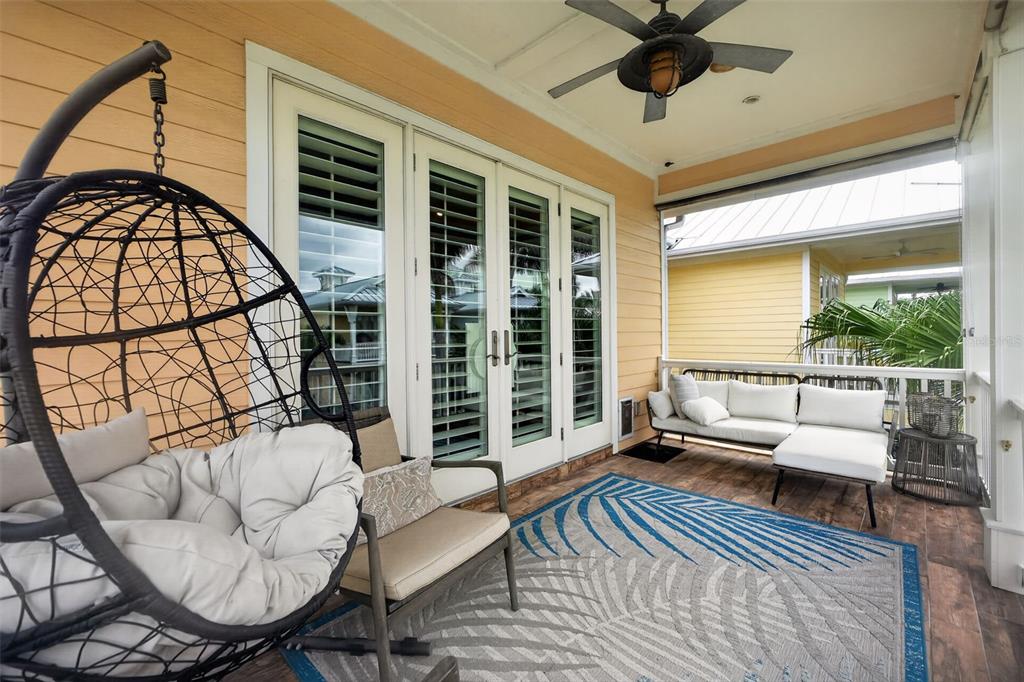 A covered patio features a hanging egg chair, outdoor sofa, and a patterned area rug — 13 OLD FEGER DRIVE UNIT 13, NEW SMYRNA BEACH, FL