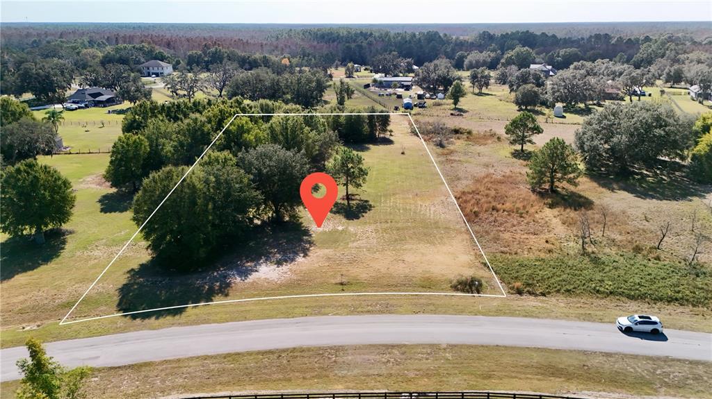 An aerial view shows a vacant, partially wooded residential lot outlined in white — GREENGROVE BOULEVARD, CLERMONT, FL