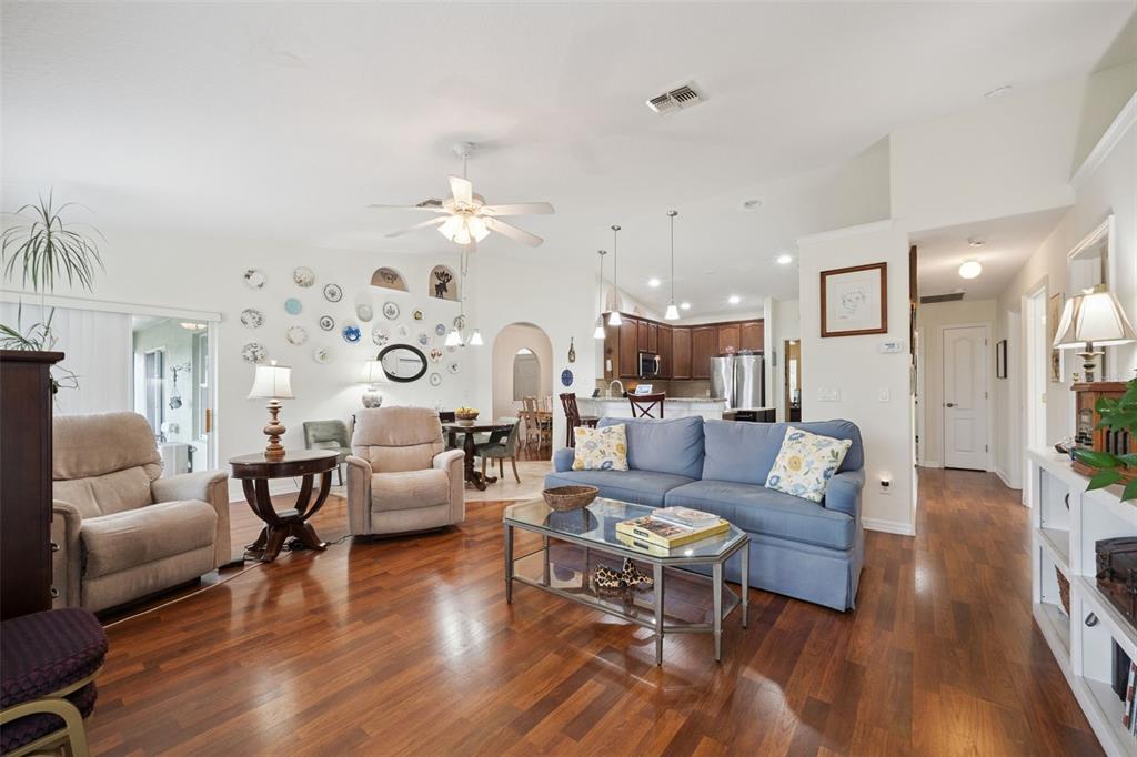 A living room with hardwood floors, a blue sofa, and a wall of decorative plates — 2243 WOLF RIDGE LANE, MOUNT DORA, FL