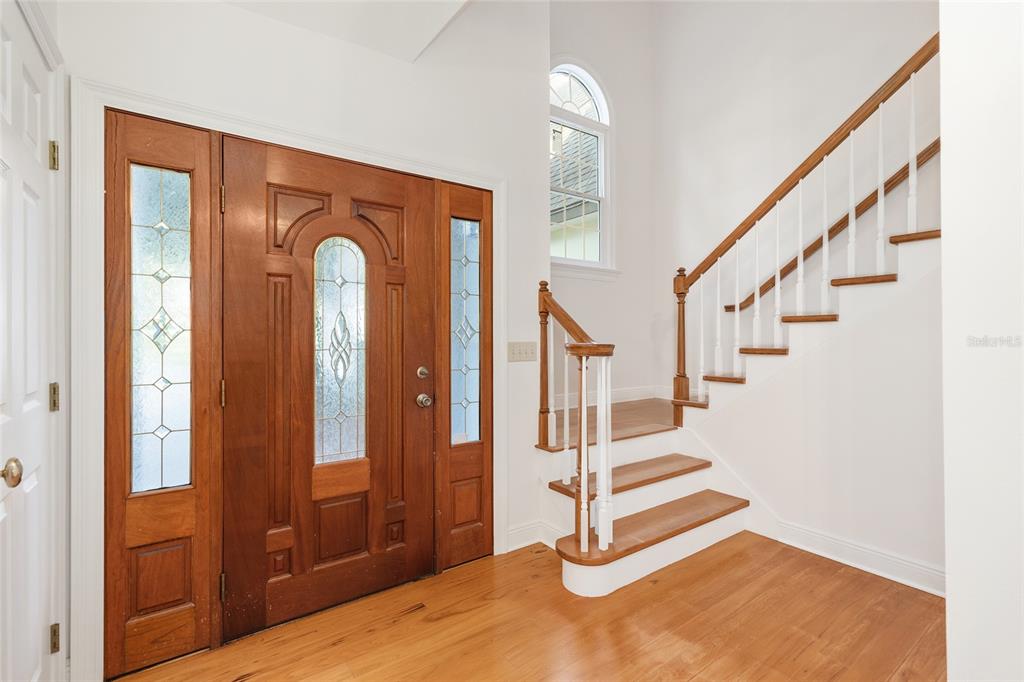An entryway features a wooden front door, hardwood floors, and a staircase with white railings — 6581 S MAGNOLIA AVENUE, OCALA, FL