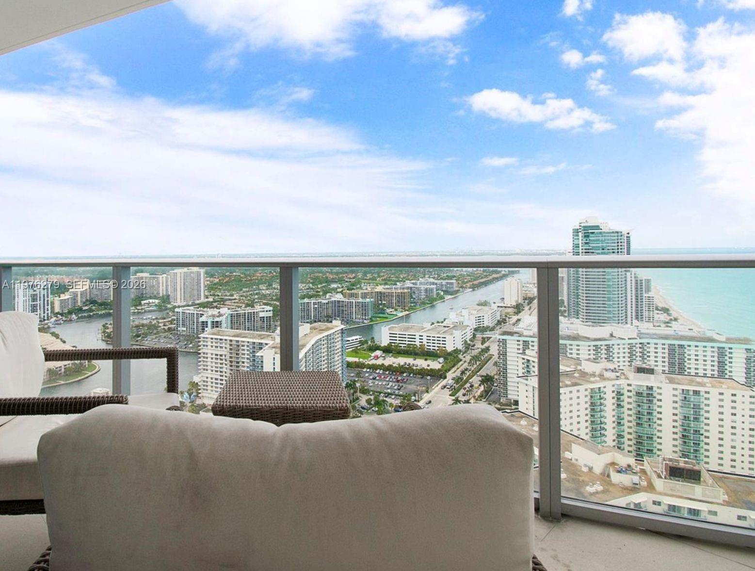 A balcony with outdoor seating overlooks a coastal city skyline and the ocean — 4111 S Ocean Dr # 3704, Hollywood FL 33019, HOLLYWOOD, FL