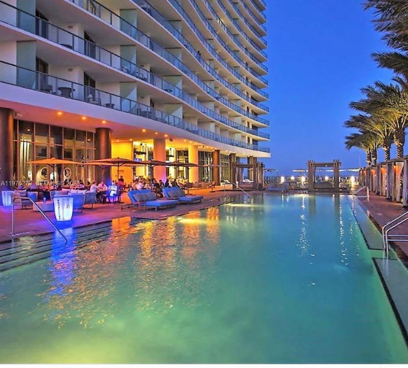 A large swimming pool sits in front of a multi-story hotel building at twilight — 4111 S Ocean Dr # 3704, Hollywood FL 33019, HOLLYWOOD, FL
