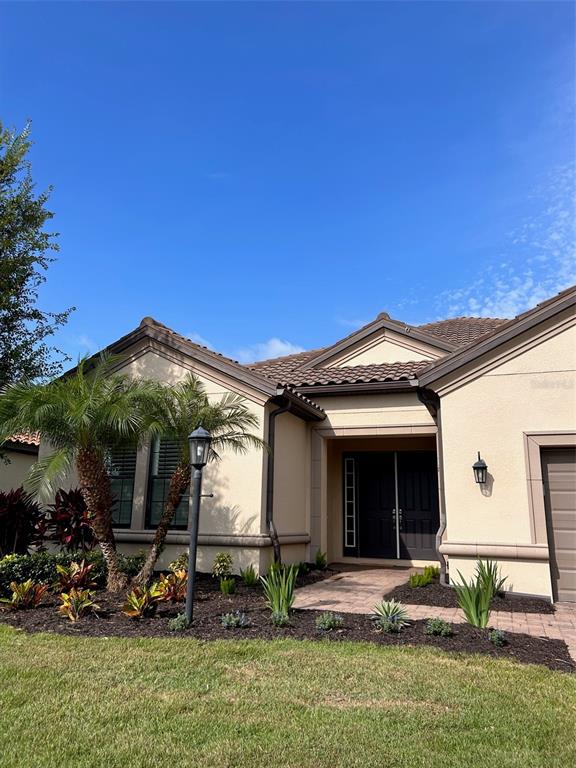 The exterior of a beige stucco house features a tiled roof, palm tree, and entryway — 5006 TIVOLI RUN, LAKEWOOD RANCH, FL