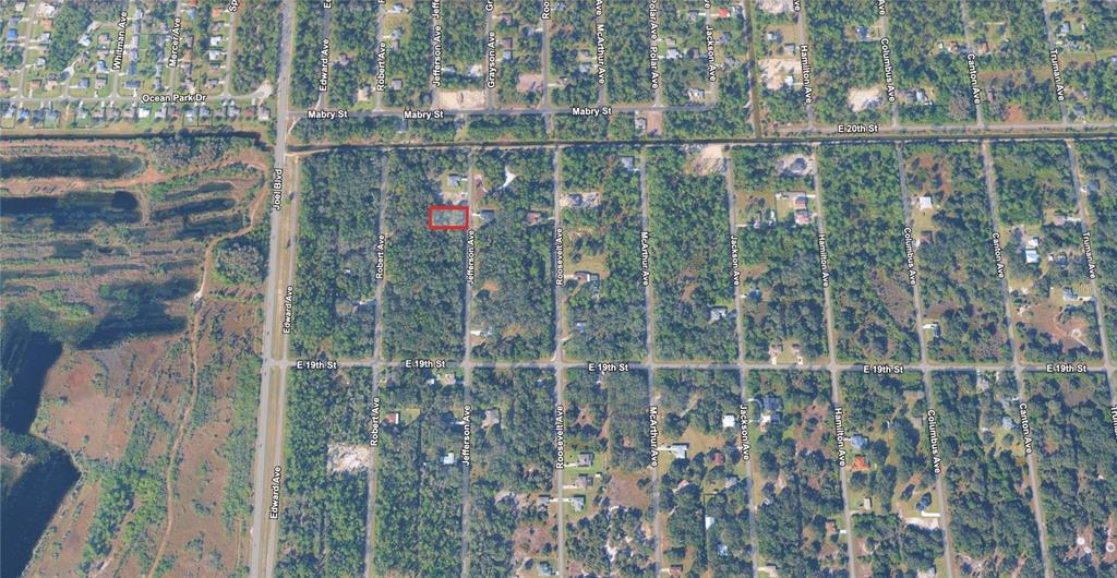 This is an aerial map view showing a highlighted rectangular property lot among wooded streets — 1915 JEFFERSON AVENUE, LEHIGH ACRES, FL