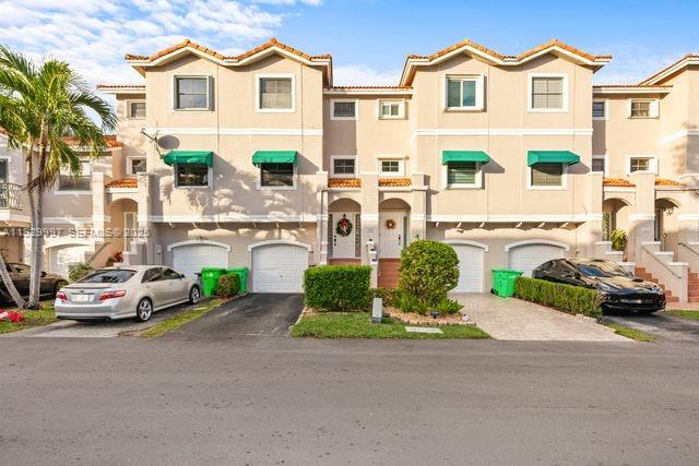 A row of multi-story townhouses features beige stucco walls, green awnings, and attached garages — 12691 NW 14th Pl, Sunrise FL 33323, SUNRISE, FL
