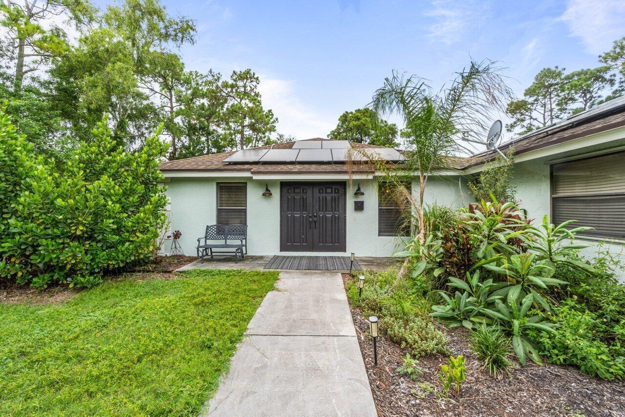 A single-story house with a light green exterior, dark double front doors, and rooftop solar panels — 3303 Custer Avenue, Lake Worth FL 33467, LAKE WORTH, FL