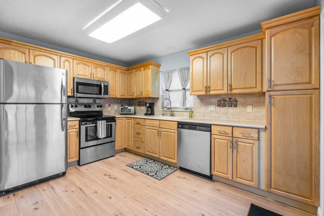 A kitchen with light wood cabinets, stainless steel appliances, and light-colored wood-look flooring — 3303 Custer Avenue, Lake Worth FL 33467, LAKE WORTH, FL