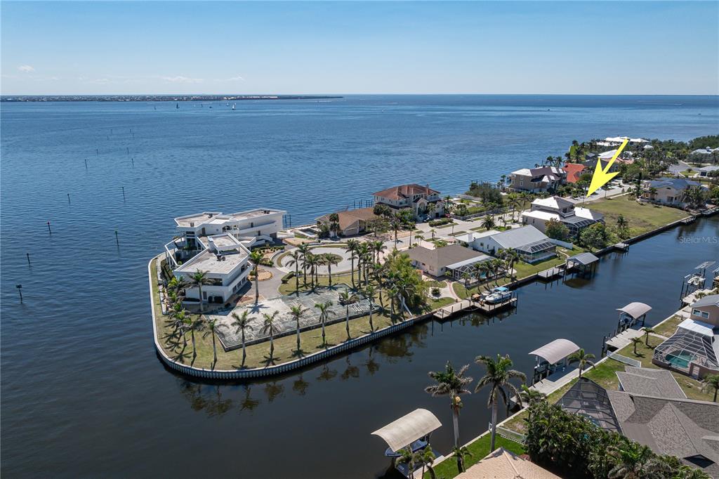 An aerial view shows waterfront homes along a canal leading into a large open bay — 250 GEORGE ROAD, PORT CHARLOTTE, FL