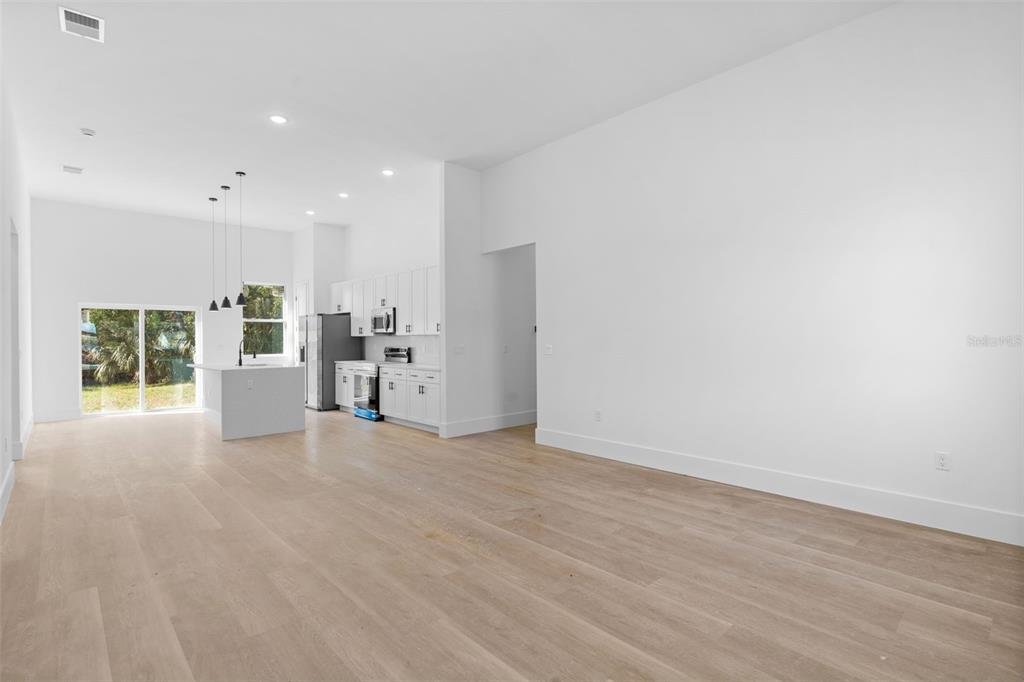 An open-concept kitchen and living area features white cabinetry, a center island, and light flooring — 543 CHAMBER STREET NW, PORT CHARLOTTE, FL