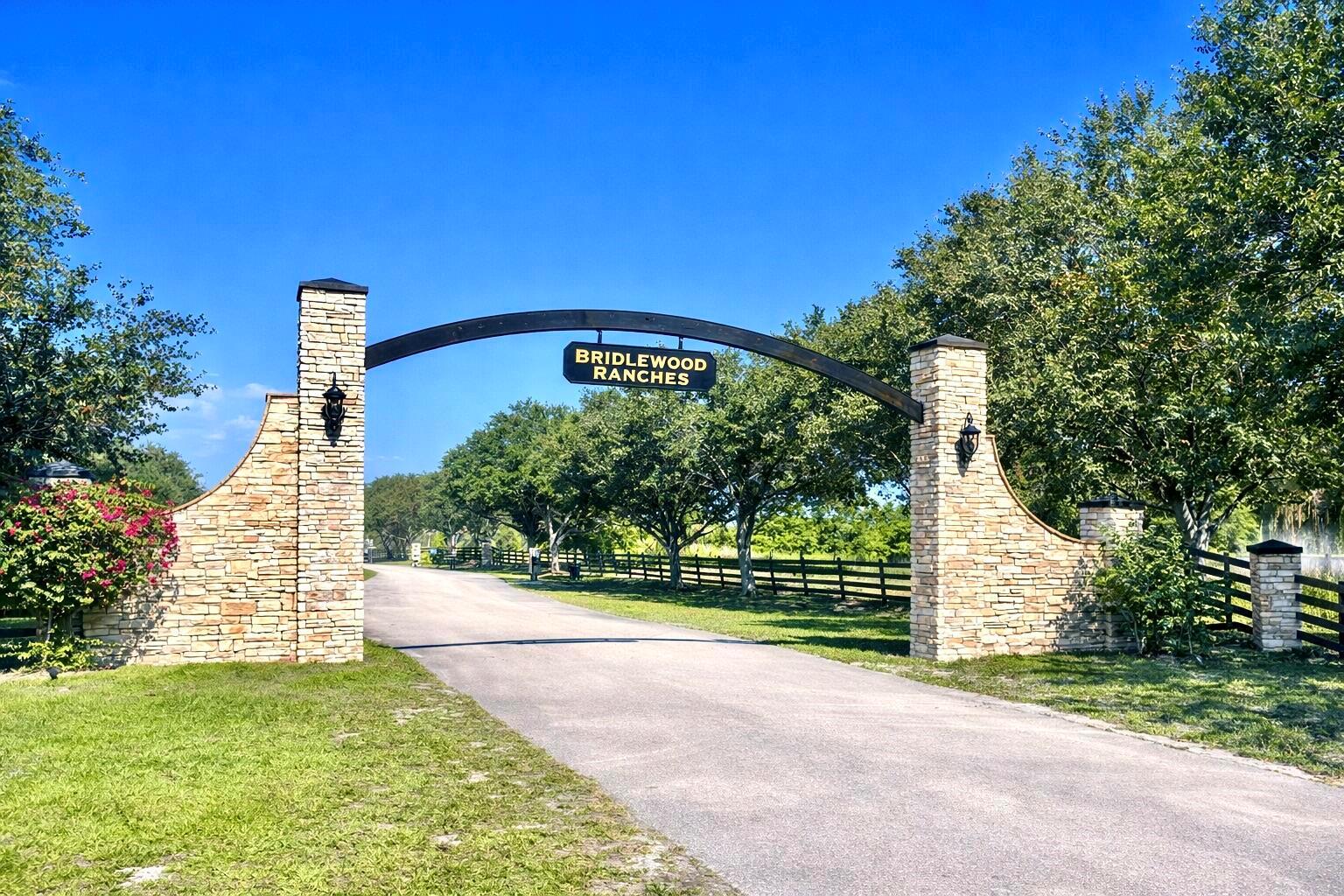 A stone entrance gate with a black arched sign reading Bridlewood Ranches spans a driveway — 2452 SE 130th Way, Okeechobee FL 34974, OKEECHOBEE, FL