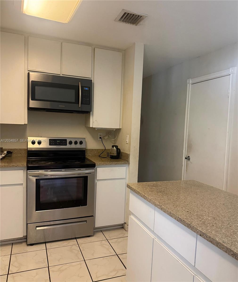 A kitchen features white cabinets, granite countertops, a center island, and tiled flooring — 767 SW 5th Ter, Florida City FL 33034, FLORIDA CITY, FL