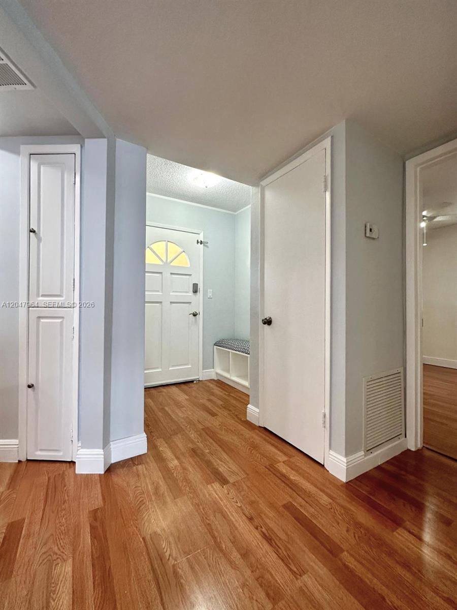 An entryway features light blue walls, wood-look flooring, a white front door, and two closets — 1300 NE 191st St # A112, Miami FL 33179, MIAMI, FL