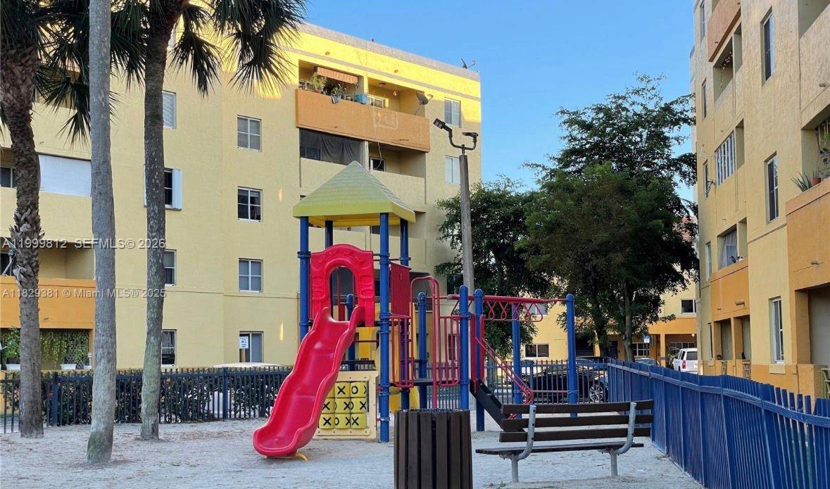 A playground with a red slide and a tic-tac-toe board sits between apartment buildings — 8270 SW 149th Ct # 209, Miami FL 33193, MIAMI, FL