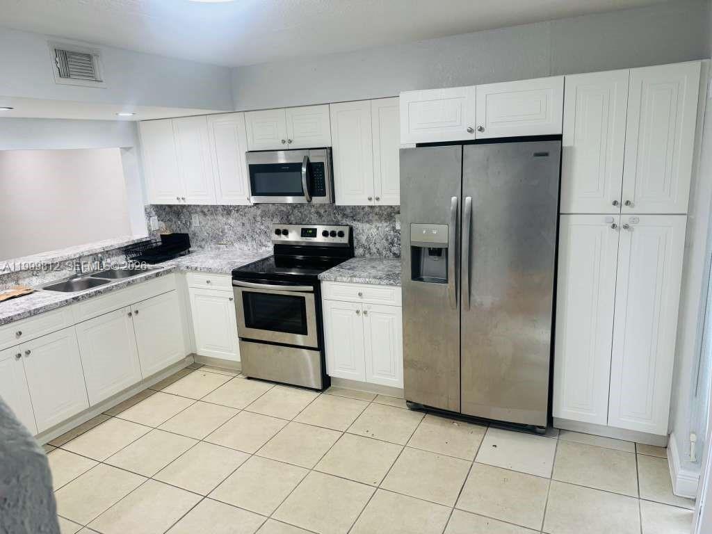 A kitchen features white cabinets, stainless steel appliances, and gray patterned countertops — 8270 SW 149th Ct # 209, Miami FL 33193, MIAMI, FL