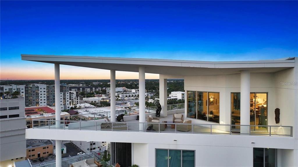 A high-rise balcony features a large covered patio area with outdoor furniture and city views — 111 S PINEAPPLE AVENUE UNIT 1210, SARASOTA, FL