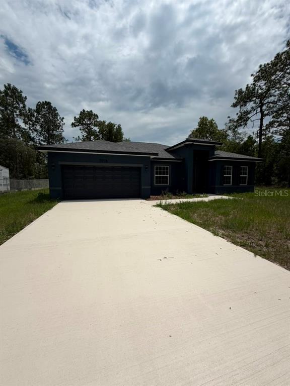 A dark-colored single-story house with a two-car garage and a concrete driveway — 5978 SW 154TH LANE ROAD, OCALA, FL