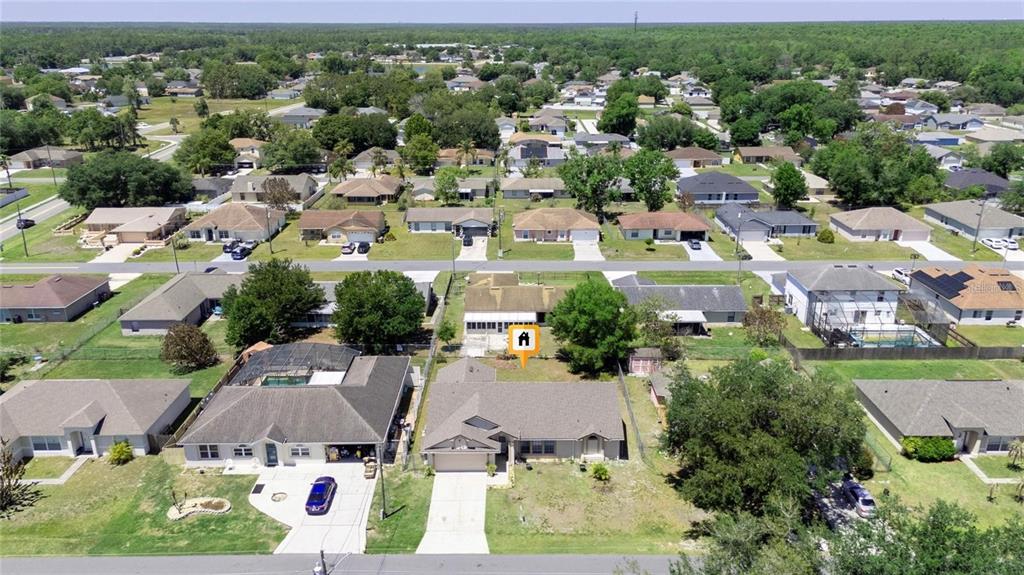 An aerial view shows a suburban neighborhood with single-family homes and a marked house — 307 COLONY COURT, KISSIMMEE, FL