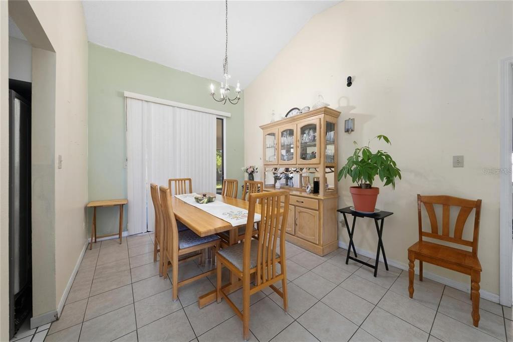 A dining room with tile floors, a wooden table and hutch, and a sliding glass door — 307 COLONY COURT, KISSIMMEE, FL