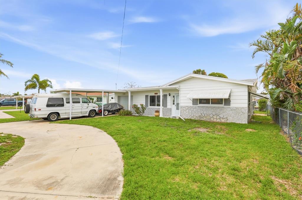 A single-story house with a white exterior, stone facade, and a carport with a van — 13538 LESLIE DRIVE, HUDSON, FL