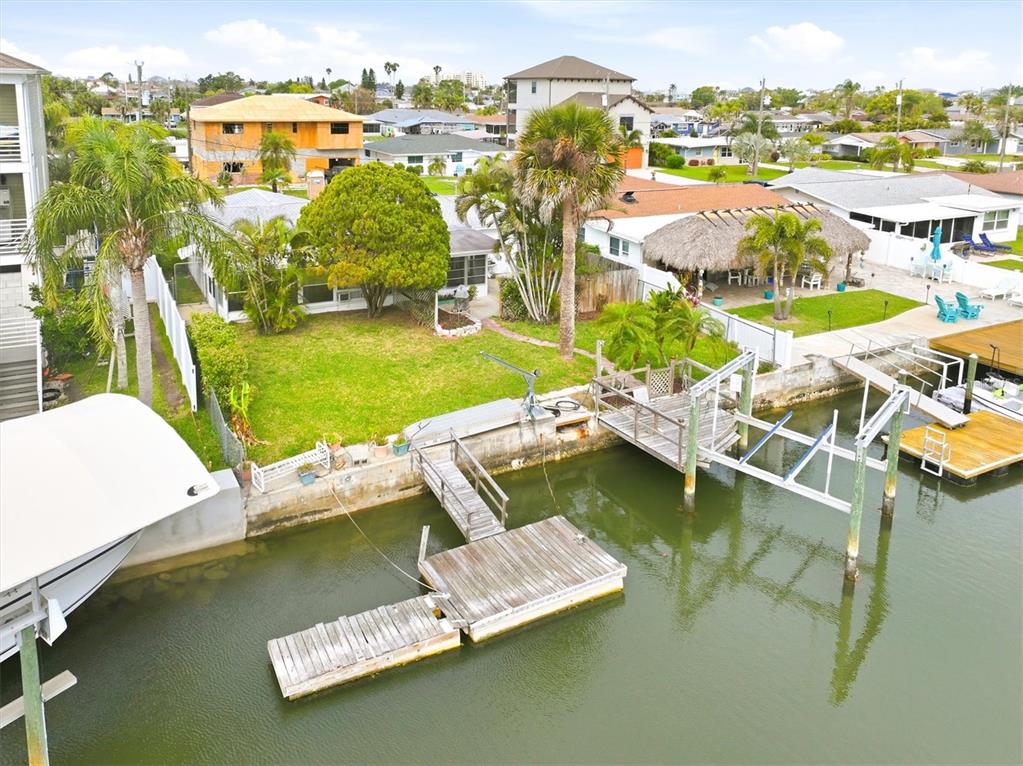 An aerial view shows a waterfront house with a lawn, palm trees, and a dock — 13538 LESLIE DRIVE, HUDSON, FL