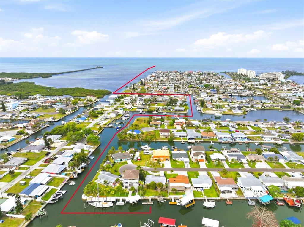 A wooden dock extends into a canal lined with boat slips and residential properties — 13538 LESLIE DRIVE, HUDSON, FL