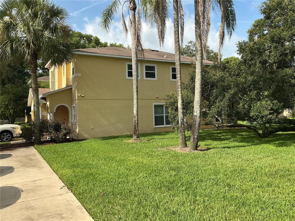 A two-story yellow house with a palm tree-lined lawn and a concrete driveway — 5308 ALOHA SEED DRIVE, SEFFNER, FL