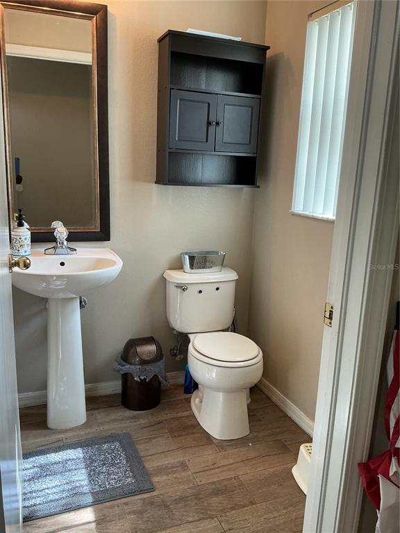 A small bathroom features a pedestal sink, a toilet, and a dark wall-mounted cabinet — 5308 ALOHA SEED DRIVE, SEFFNER, FL