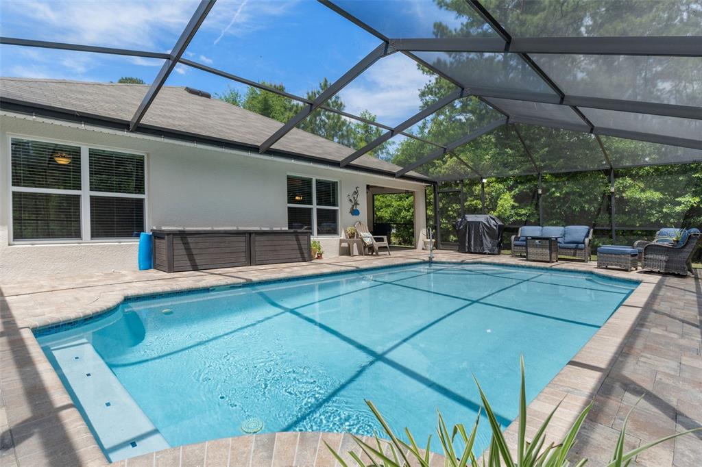 A swimming pool with a screened enclosure sits on a patio next to a house — 17528 GARSALASO CIRCLE, BROOKSVILLE, FL