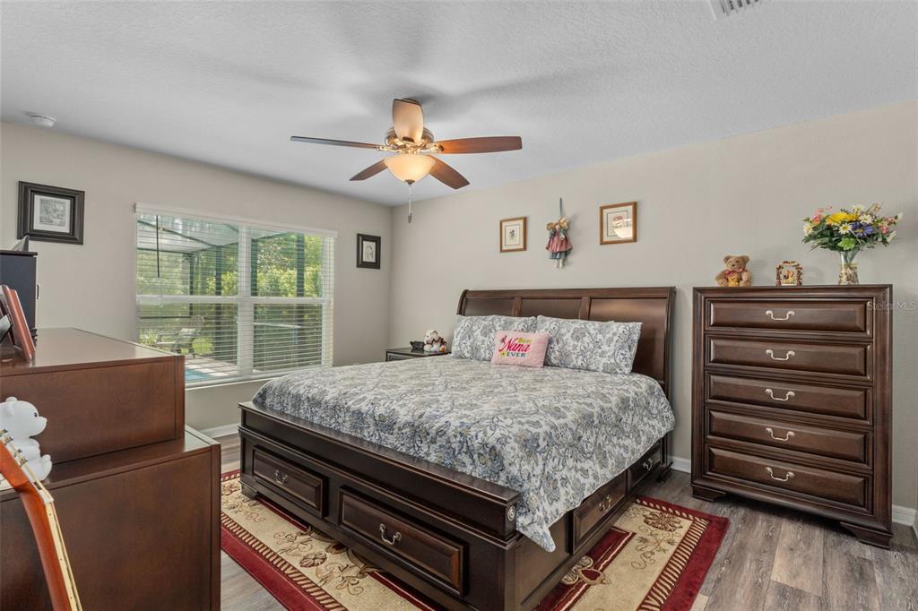 A bedroom features a dark wood bed frame, matching dresser, and a ceiling fan — 17528 GARSALASO CIRCLE, BROOKSVILLE, FL