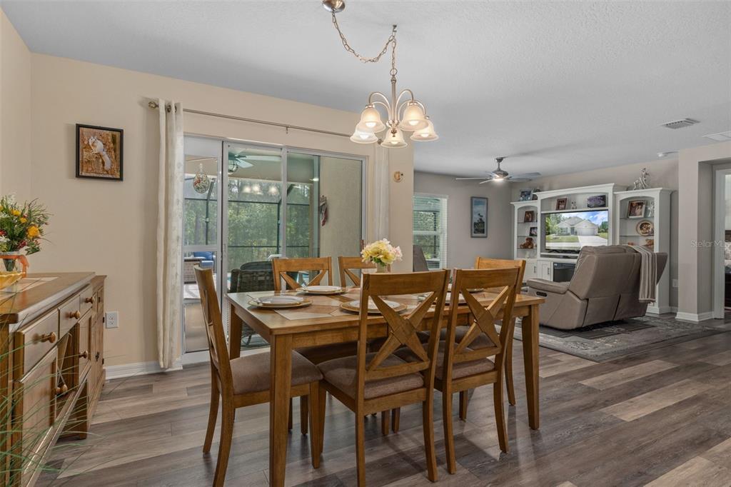 A dining area with a wooden table and chairs sits adjacent to a living room — 17528 GARSALASO CIRCLE, BROOKSVILLE, FL