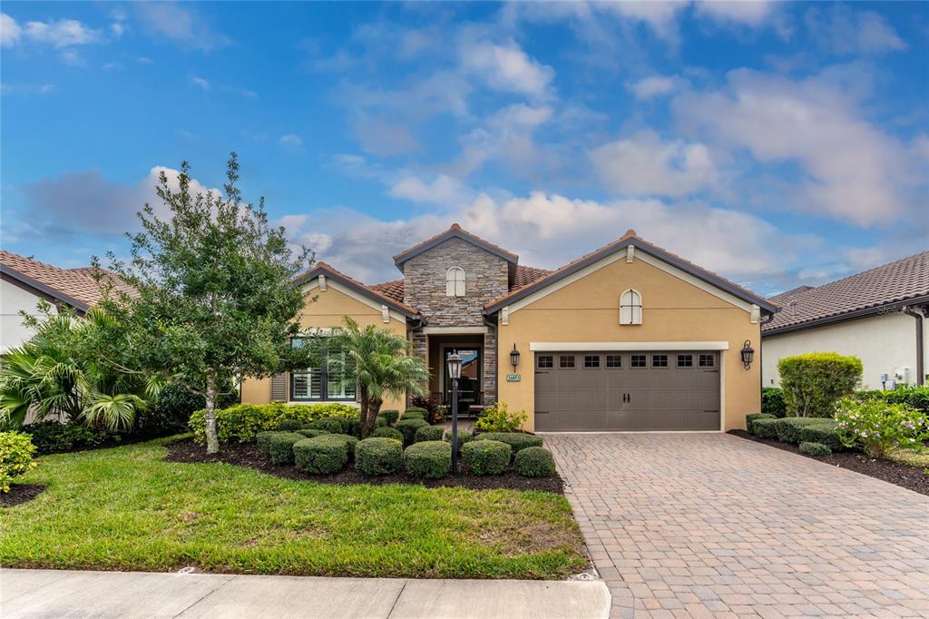 A single-story house with a stone facade, tan stucco walls, and a paved driveway — 26853 WEISKOPF DRIVE, ENGLEWOOD, FL