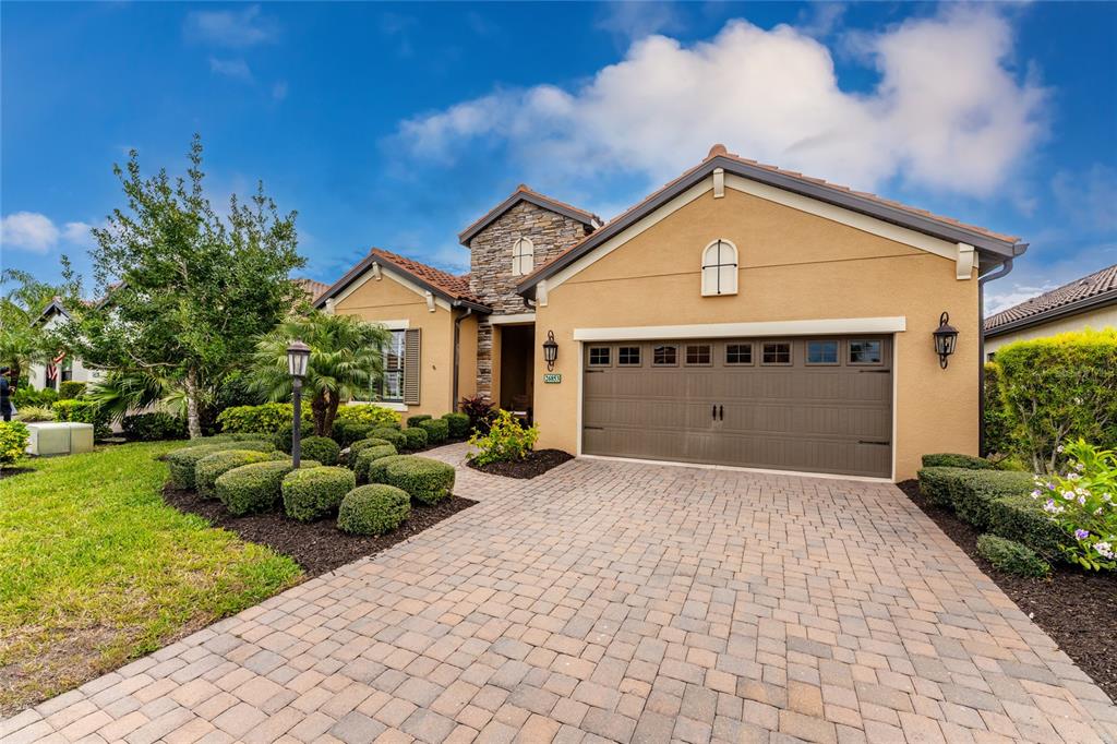 A single-story house with a tan stucco exterior, stone accents, and a paved driveway — 26853 WEISKOPF DRIVE, ENGLEWOOD, FL