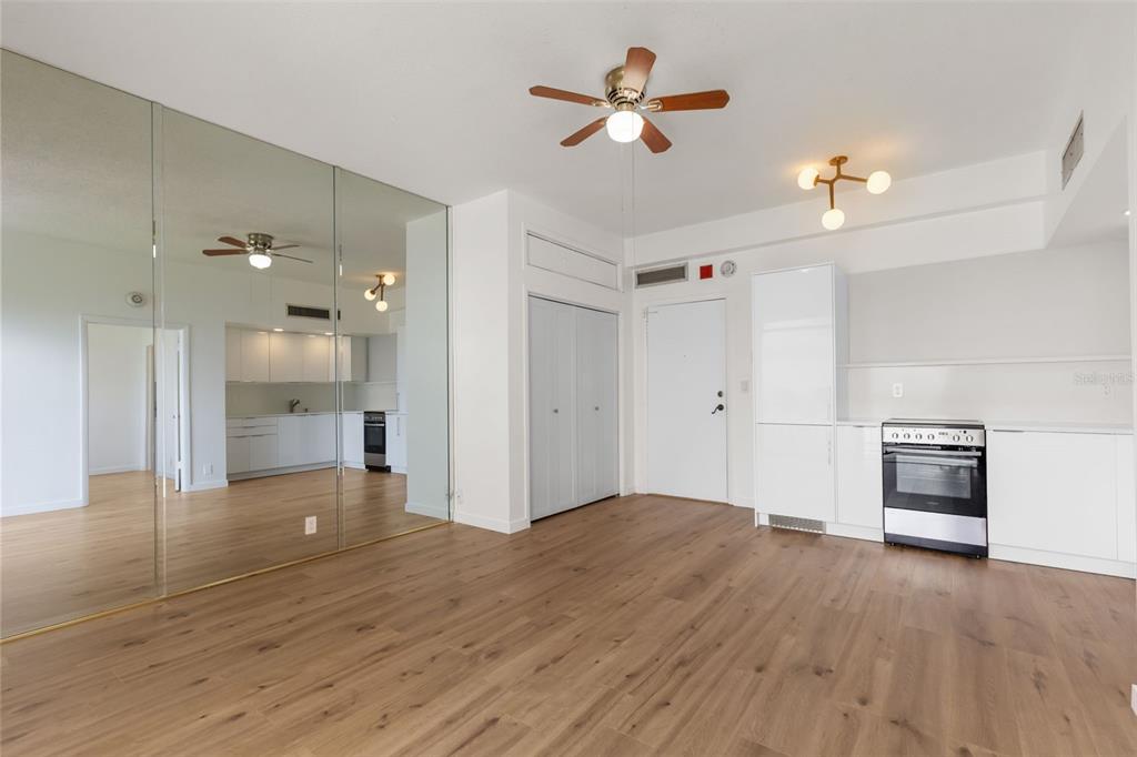 A room with light wood flooring, mirrored closet doors, a ceiling fan, and a kitchen area — 2109 BAYSHORE BOULEVARD UNIT 503, TAMPA, FL