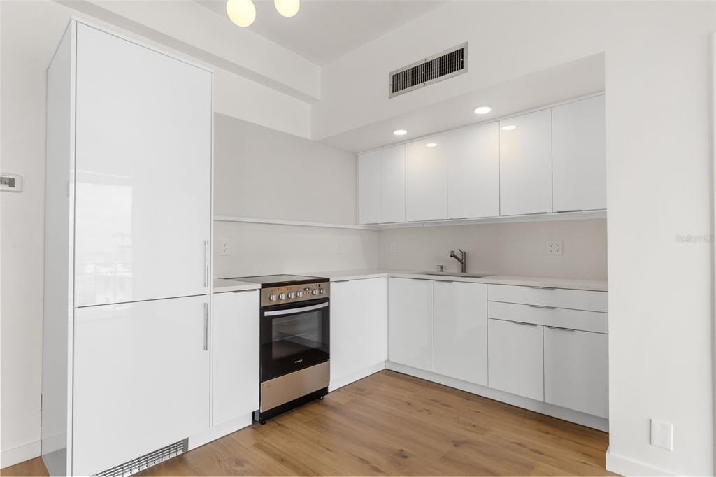 A modern kitchen features white cabinetry, stainless steel appliances, and light wood-look flooring — 2109 BAYSHORE BOULEVARD UNIT 503, TAMPA, FL