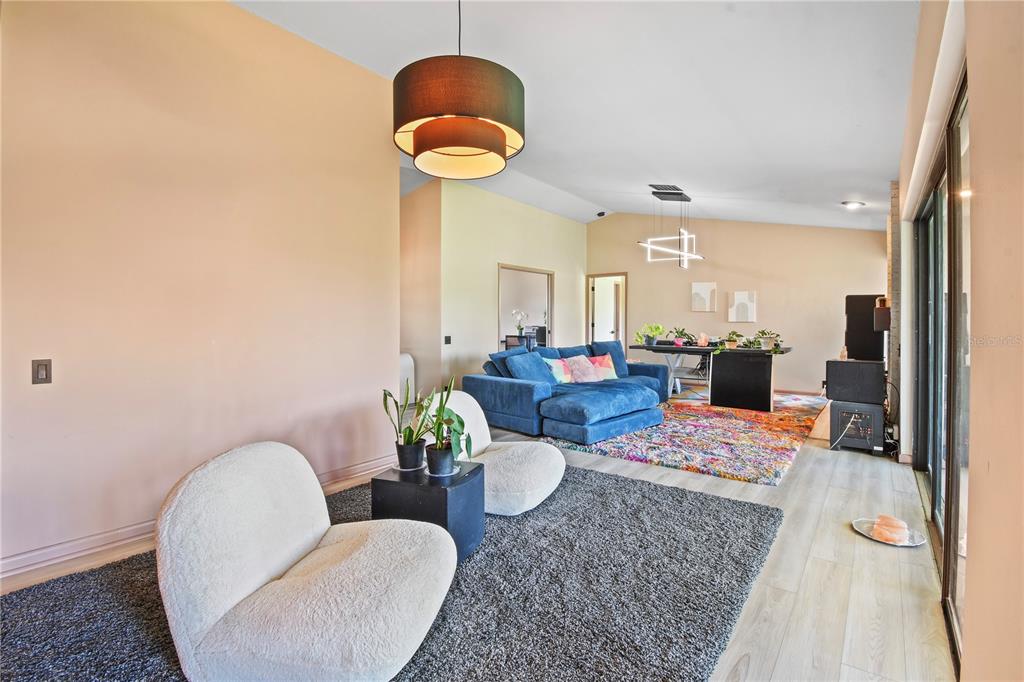 A living room features two white chairs, a blue sectional, and a colorful area rug — 2906 WINDRIDGE DRIVE, HOLIDAY, FL