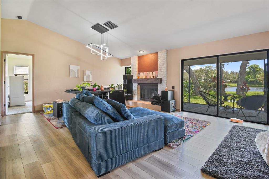 A living room features a blue sectional sofa, a fireplace, and sliding doors to a patio — 2906 WINDRIDGE DRIVE, HOLIDAY, FL