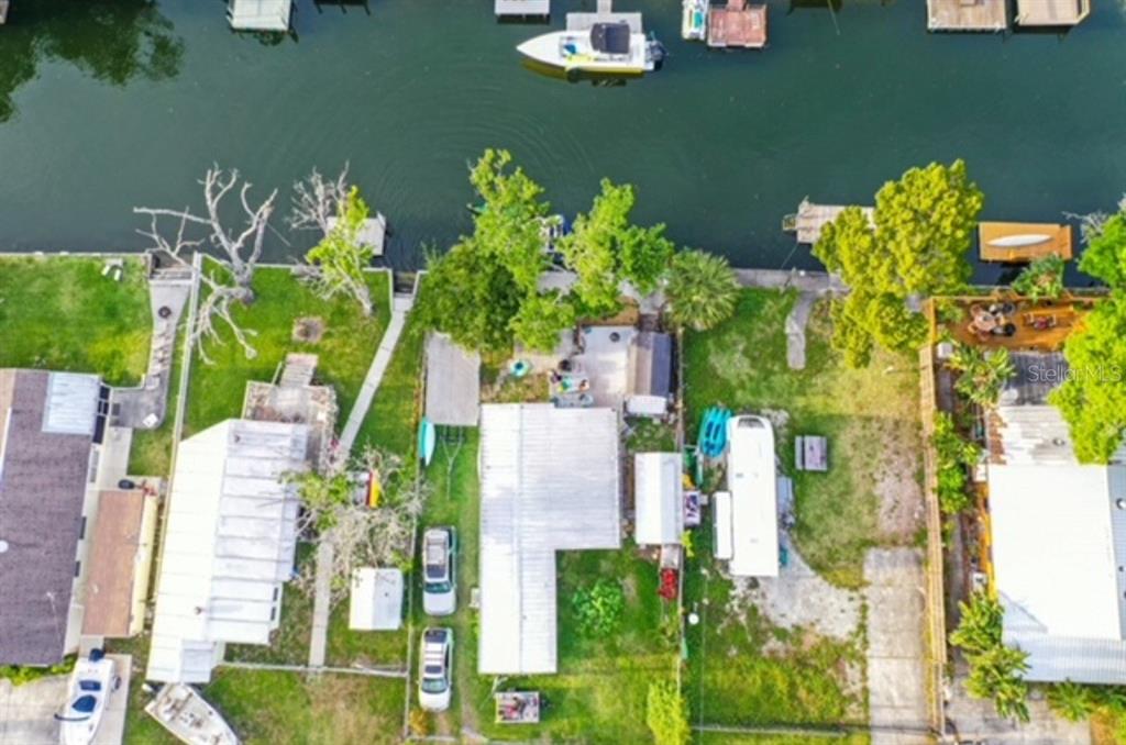 An aerial view shows a waterfront property with a house, yard, and private boat dock — 5418 CIRCLE DRIVE, WEEKI WACHEE, FL