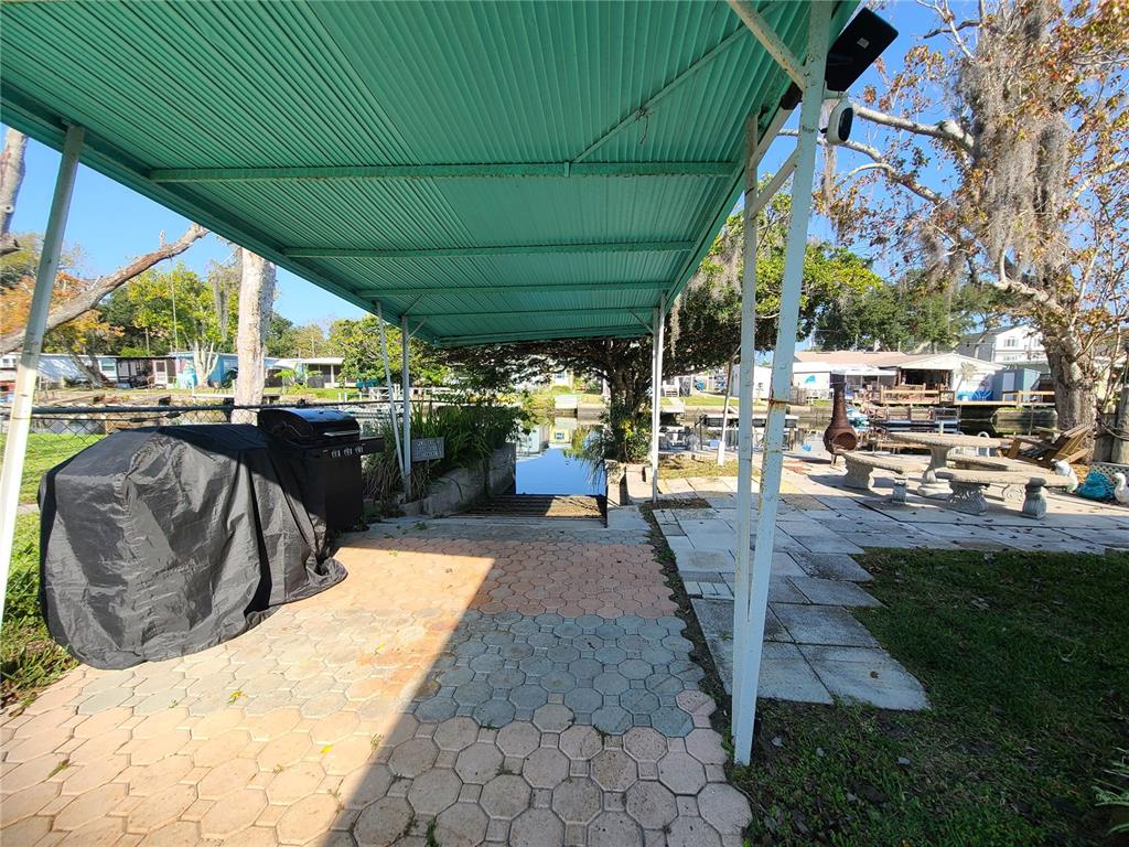 A covered patio area features a paved walkway leading to a boat slip and canal — 5418 CIRCLE DRIVE, WEEKI WACHEE, FL