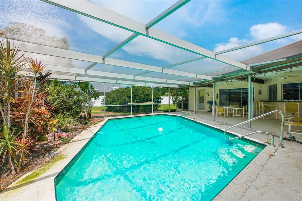 A rectangular swimming pool enclosed by a screened lanai with a concrete patio area — 2768 NORTHRIDGE DRIVE E, CLEARWATER, FL